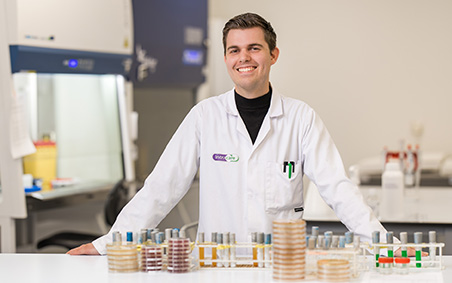 Sem in his lab coat with petri dishes in lab